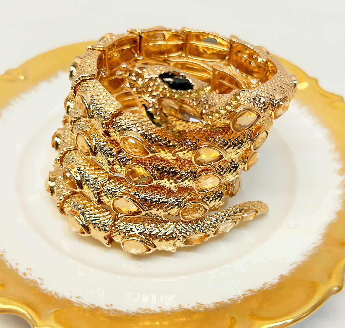 Statement style snake coil style bracelet with black & gold colored crystal accents.