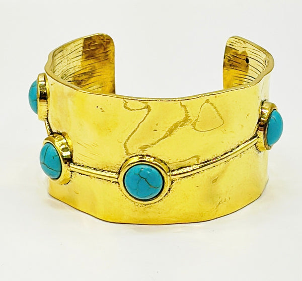 Gold metal tone hammered style statement cuff with faux turquoise stone accents.