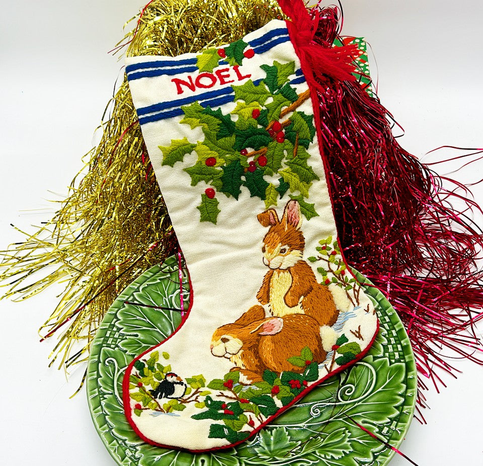 Vintage 1980s era hand, stitch Christmas stocking with bunnies and Holly that reads Noel.