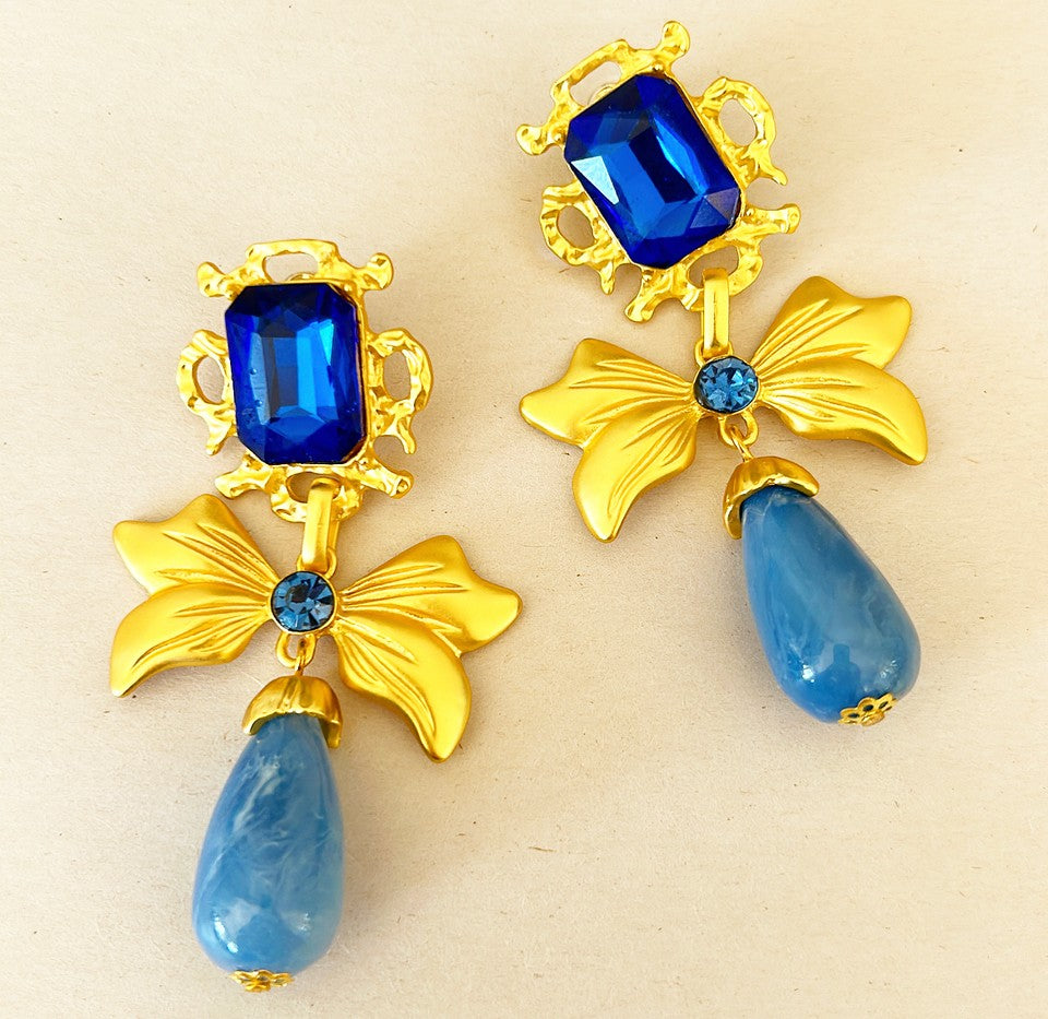 Larger statement pierced style earrings with bow design and dangling bottoms.