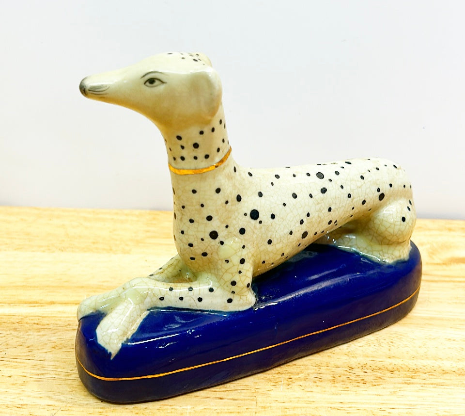 Classic vintage Staffordshire style dog laying on oval blue base