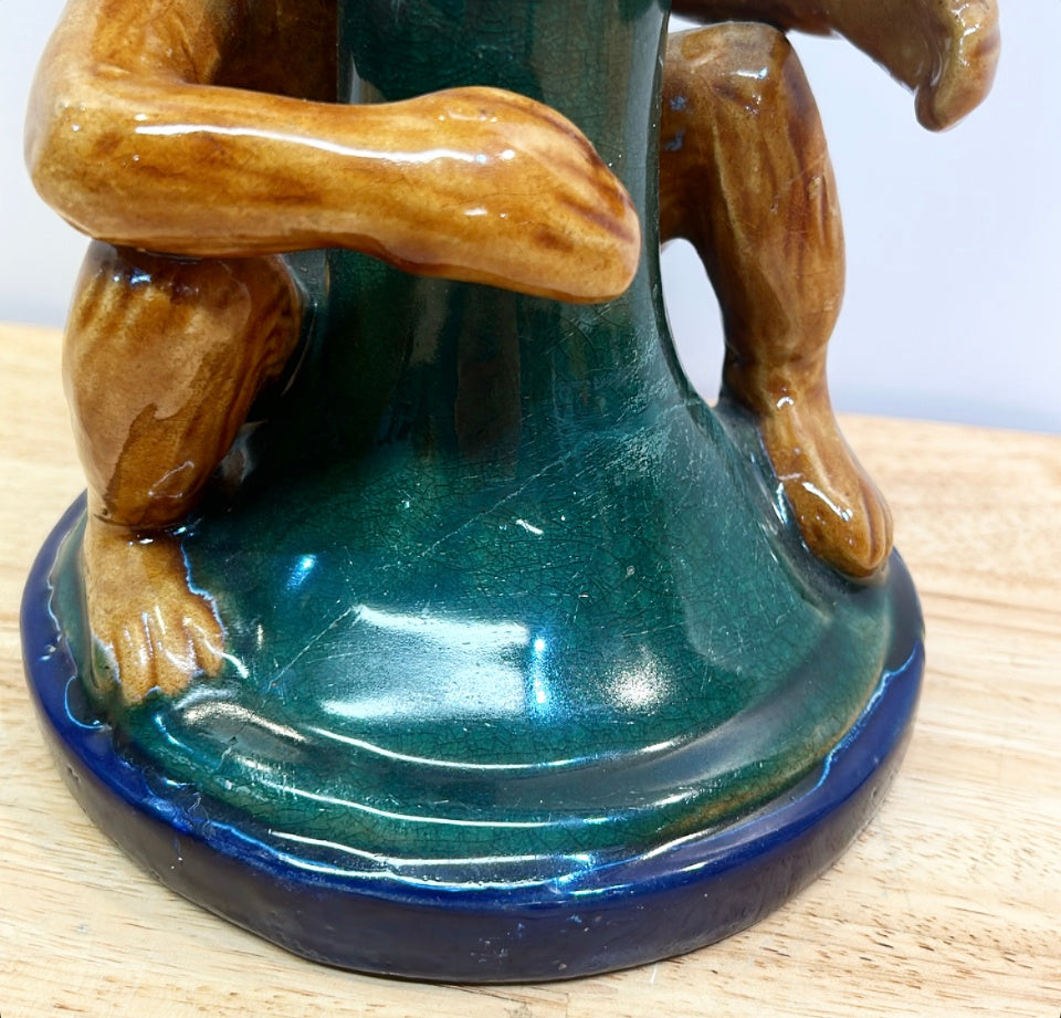 Decorative chinoiserie style monkey hugging palm tree candlestick.