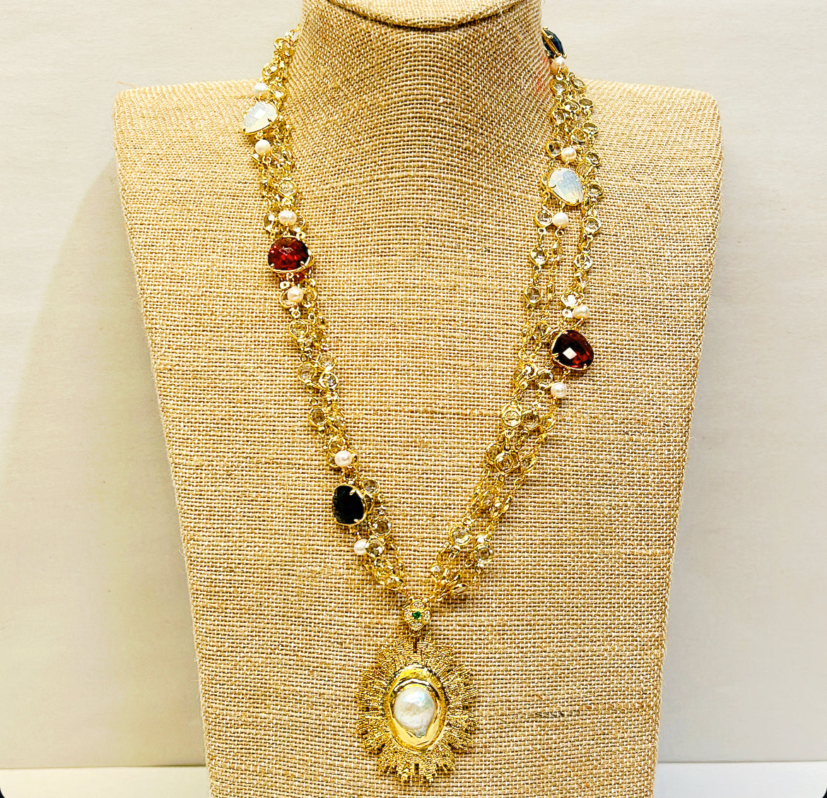 Multi chain layered style statement next. Faux pearl oval starburst pendant with clear crystal accents mixed with larger red, green &amp; opaque style crystals.